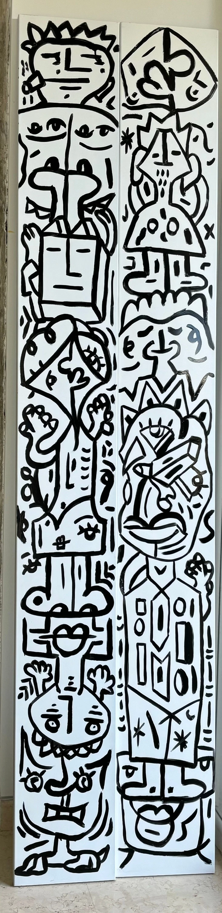 Dos paneles altos y estrechos con rostros apilados en columna, dibujados en trazos negros gruesos sobre fondo blanco. Díptico. Esmalte sobre lienzo, 60 x 240 cm, 2023. Caracas. Nicolás Lapadula