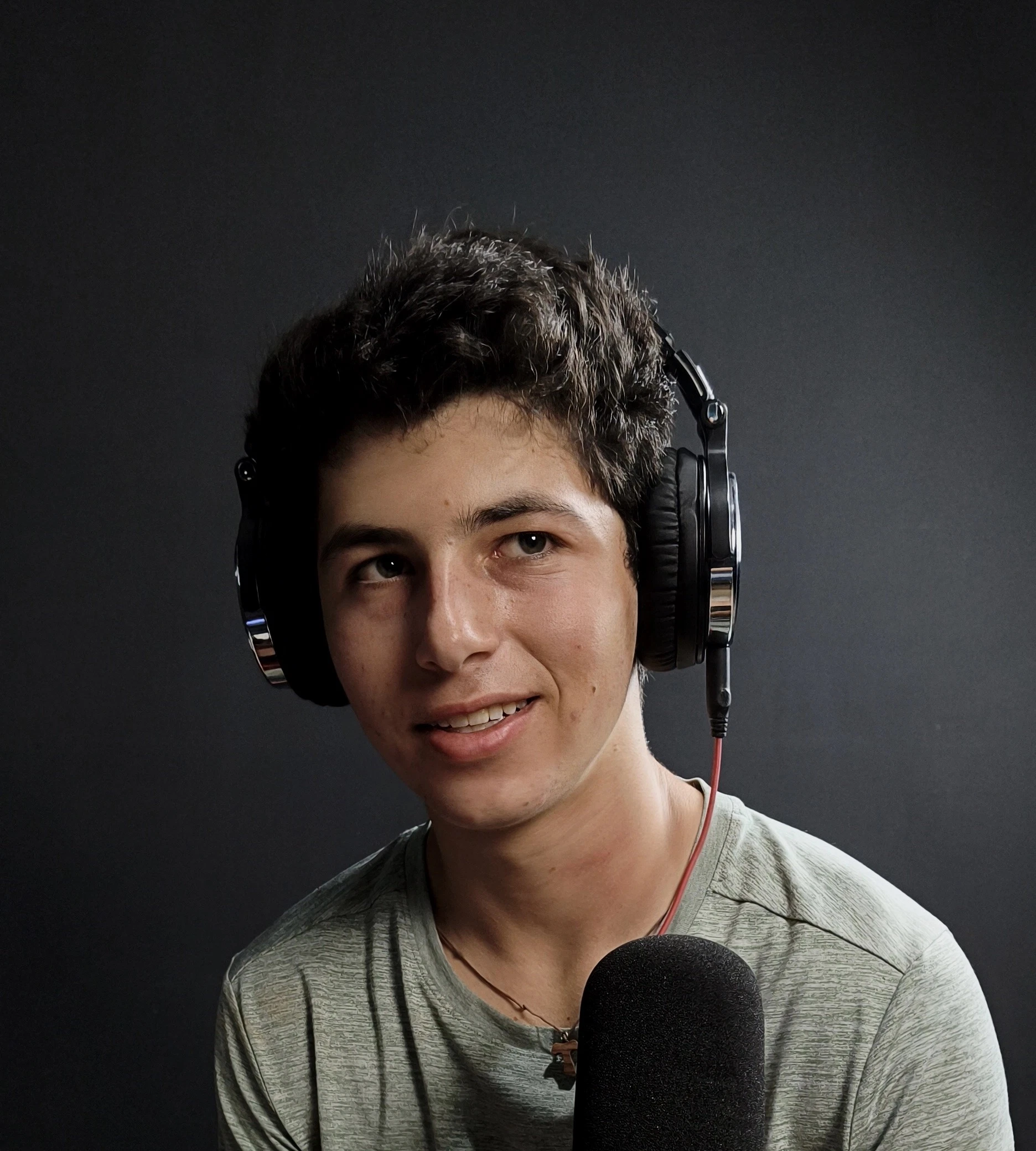 Nico sonriendo en un estudio, con audífonos, detrás de un micrófono.