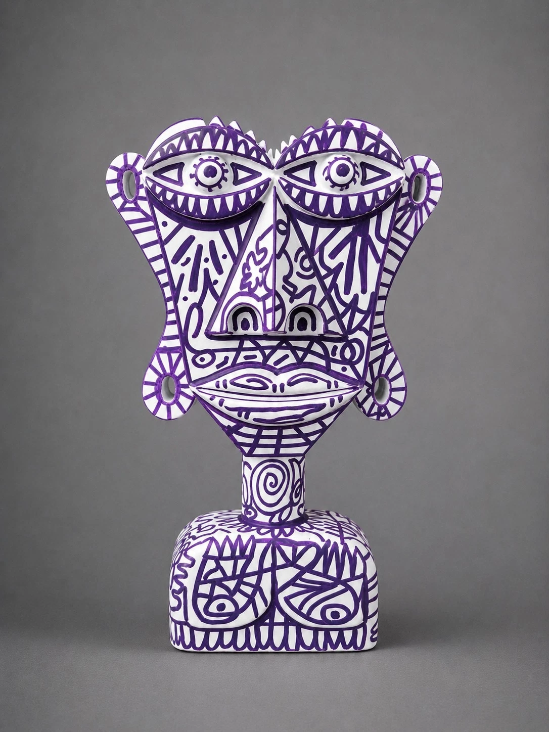Busto blanco de rostro frontal con ojos grandes y labios gruesos, cubierto de dibujos lineales en morado, sobre fondo gris. Sin título. Nicolás Lapadula