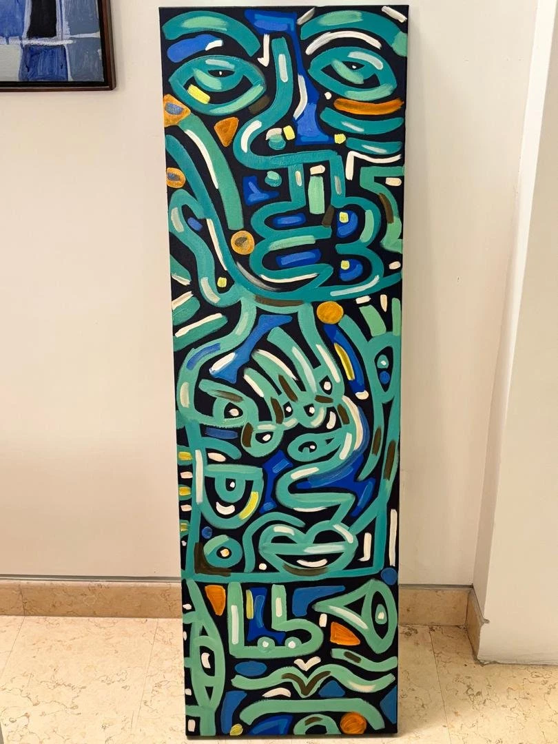Lienzo vertical con rostros apilados en trazo verde turquesa sobre fondo azul y negro, con toques naranjas, apoyado contra una pared. Sin título. Acrílico sobre lienzo, 40 x 130 cm, 2025. Caracas. Nicolás Lapadula