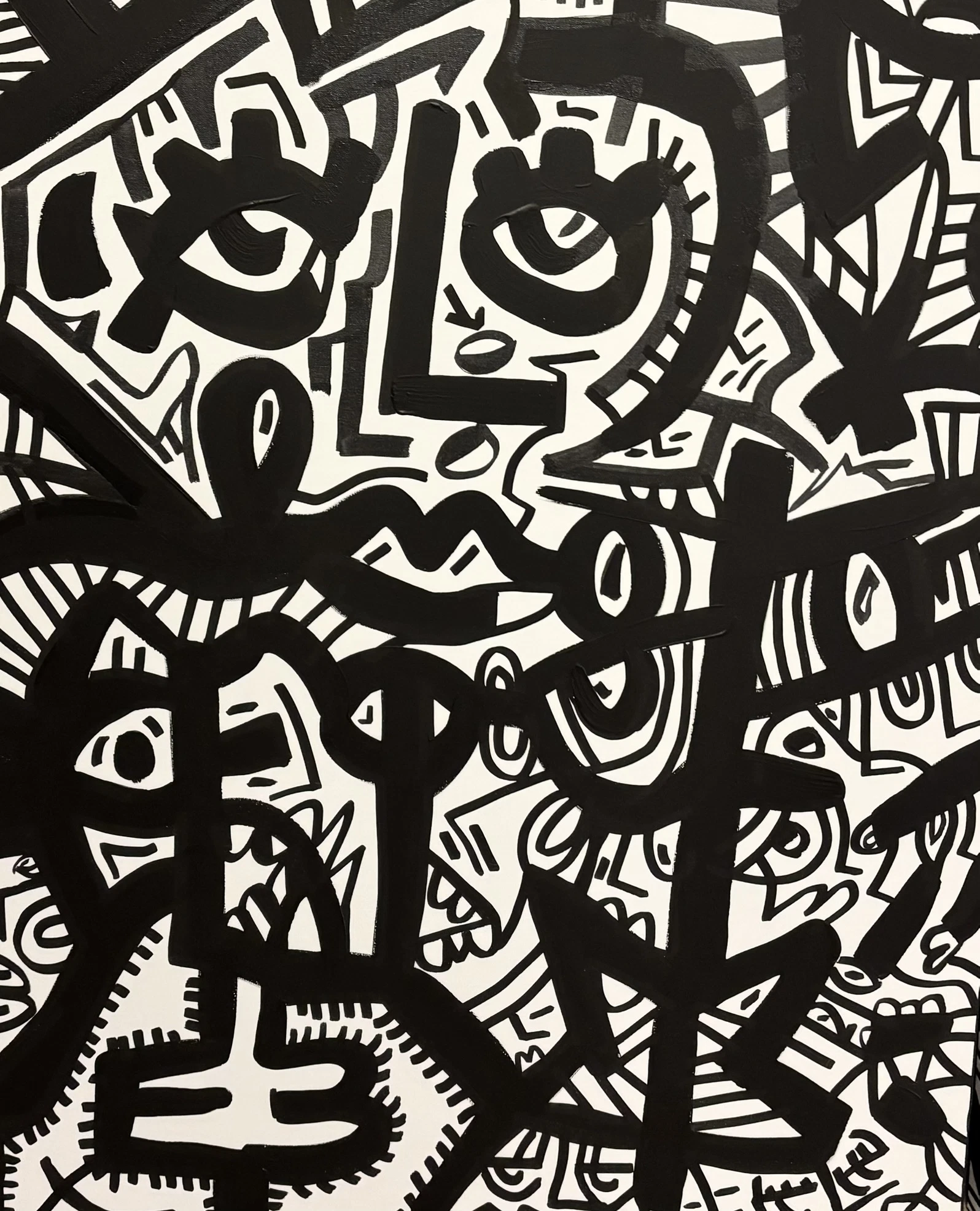 Varios rostros superpuestos en trazo negro sobre blanco; arriba dos ojos grandes con pestañas y una boca, y abajo figuras con rayas y puntos. Sin título. Acrílico sobre lienzo, 70 x 90 cm, 2026. Madrid. Nicolás Lapadula
