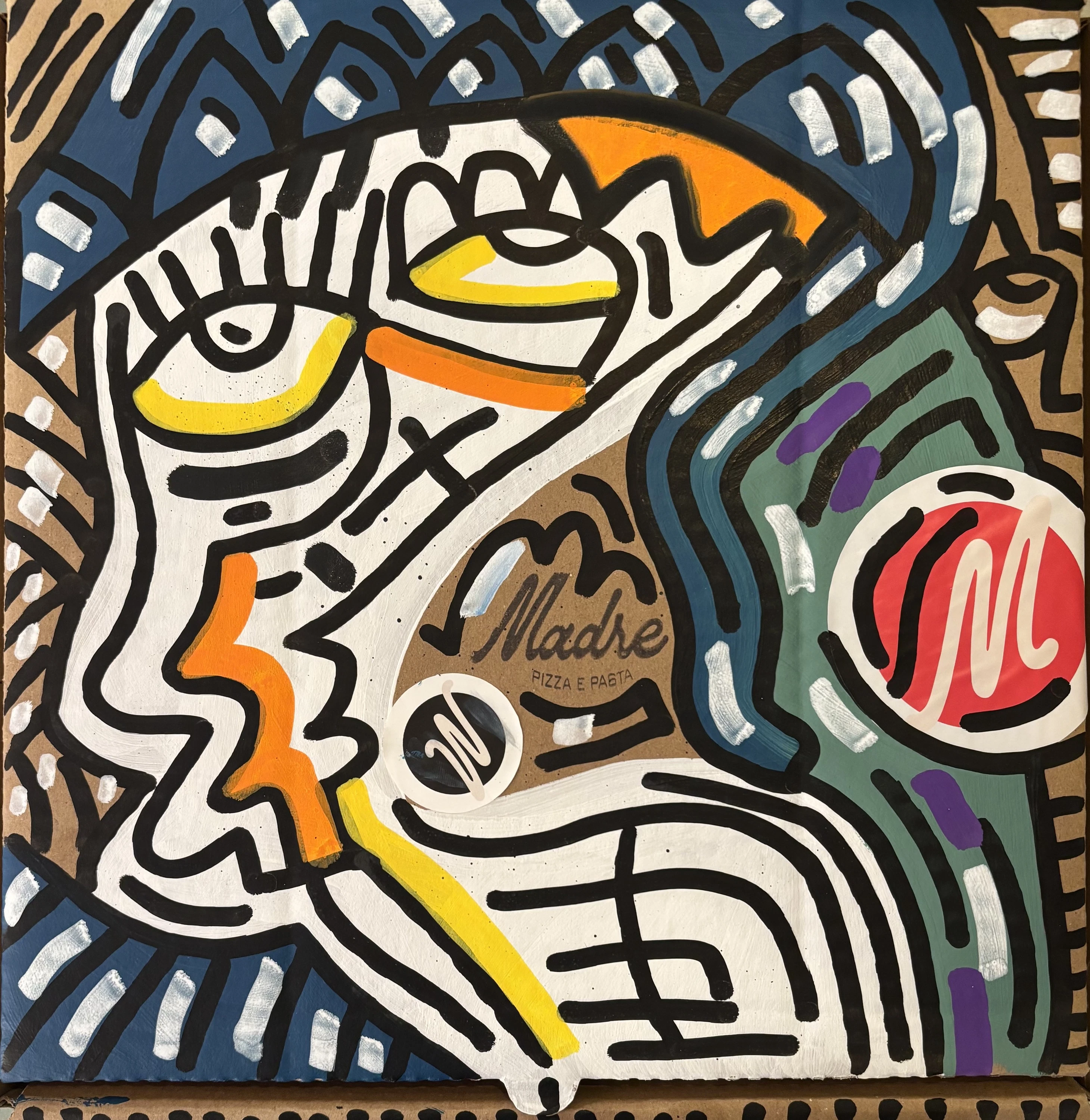 Rostro blanco de perfil con ojo amarillo y naranja, junto a un círculo rojo, sobre azul y verde, pintado en una caja de cartón. Sin título. Acrílico sobre cartón, 40 x 40 cm, 2026. Caracas. Nicolás Lapadula